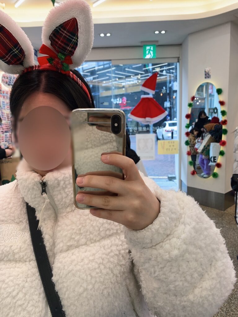 Mirror selfie wearing The North Face Sherpa Nuptse Jacket White with winter outfit and bunny headband