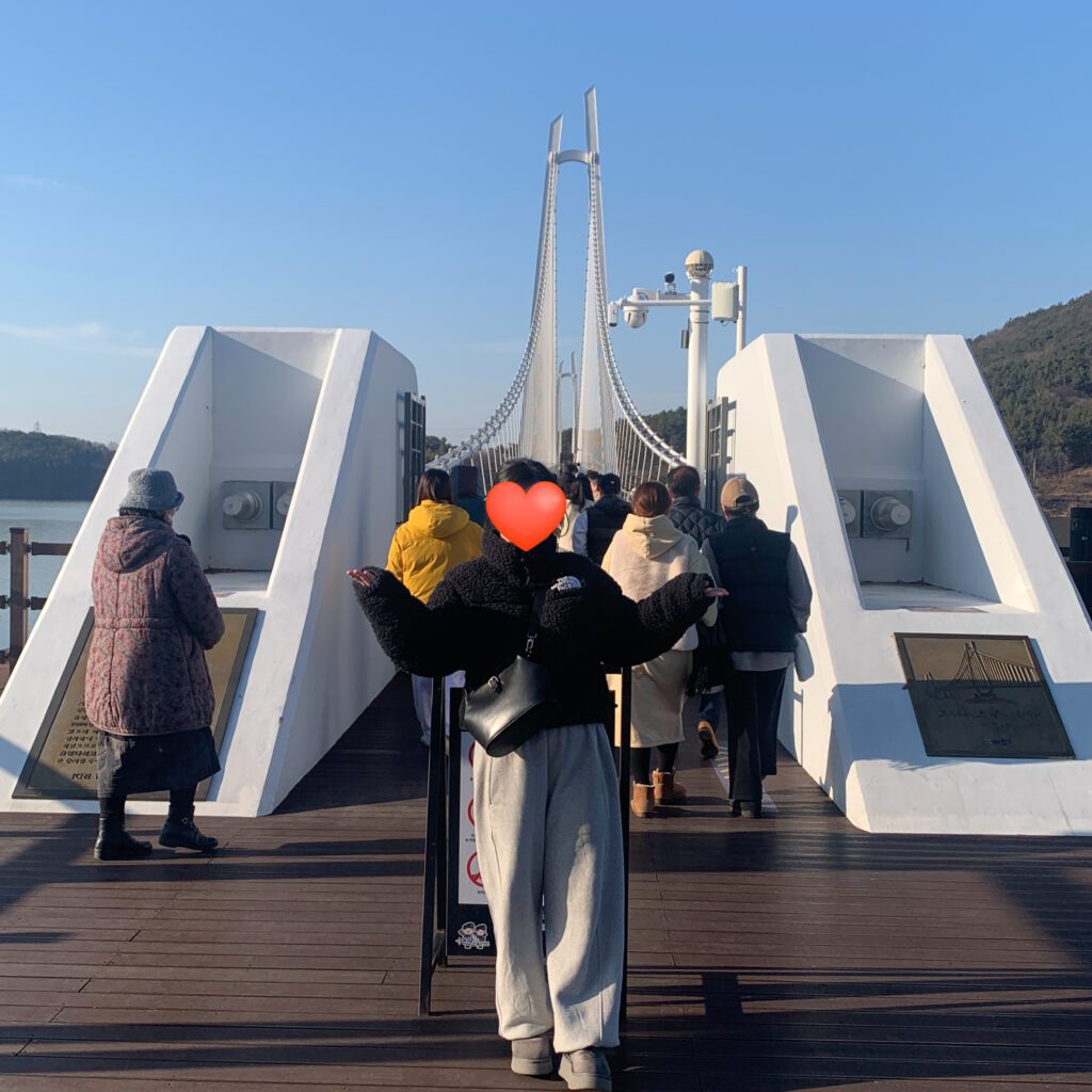 Wearing The North Face Sherpa Nuptse Jacket in black while walking by the riverside, showing cozy fleece texture and relaxed winter outfit.β