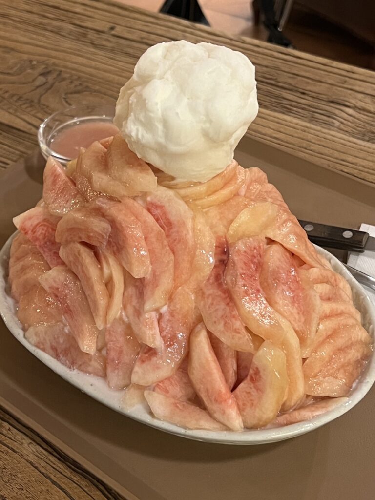 ALT: Peach bingsu with fresh fruit slices at a Songridan-gil Jamsil dessert cafe
