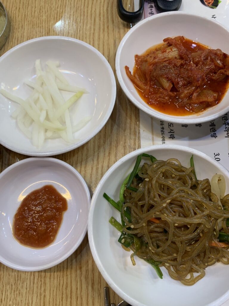 Korean kimchi, japchae, radish salad, and ssamjang side dishes