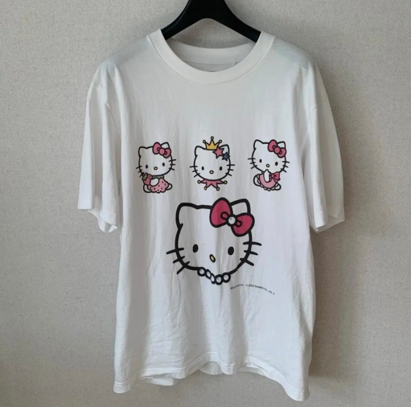 Uniqlo Hello Kitty T-shirt hanging on hanger with four Kitty designs.