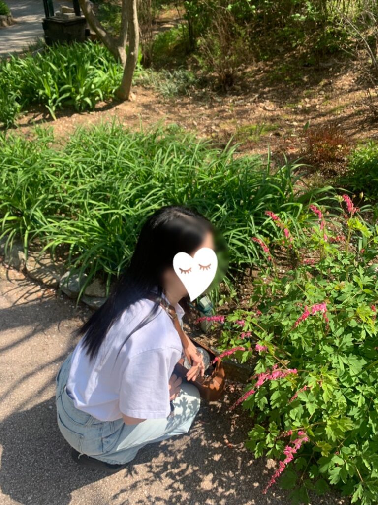crouching near flowers wearing Uniqlo Hello Kitty T-shirt outdoors.