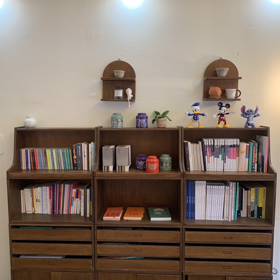 Cute figures and books on wooden shelves inside Cafe Root Gangnam