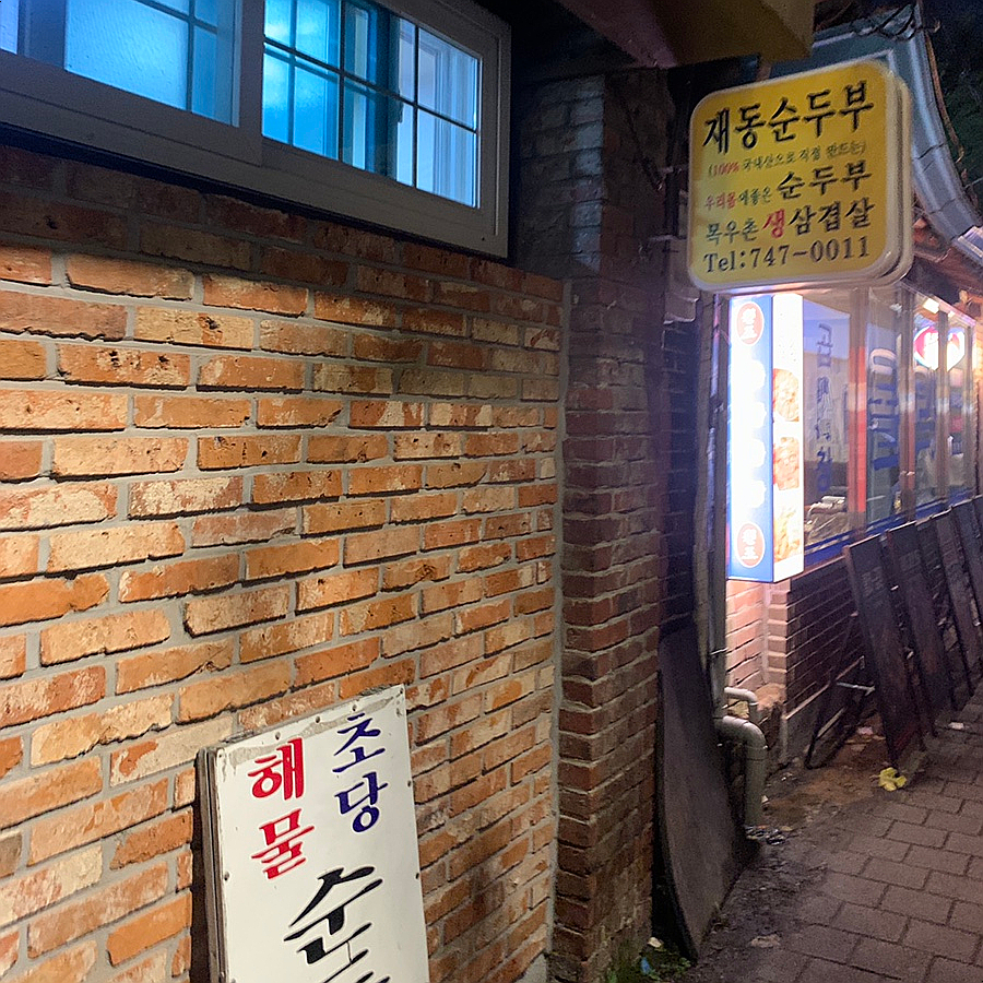 Brick exterior and entrance sign of a Bukchon Korean Restaurant in Anguk at night