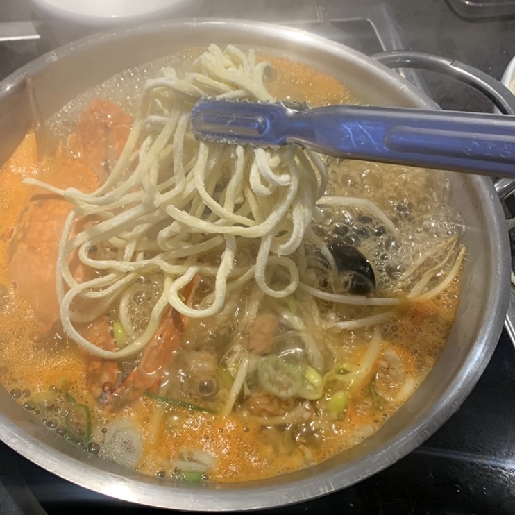 Adding noodles into seafood broth at a Jongno Bossam Restaurant