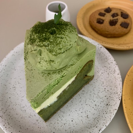 whole matcha gateau slice on plate with cookie