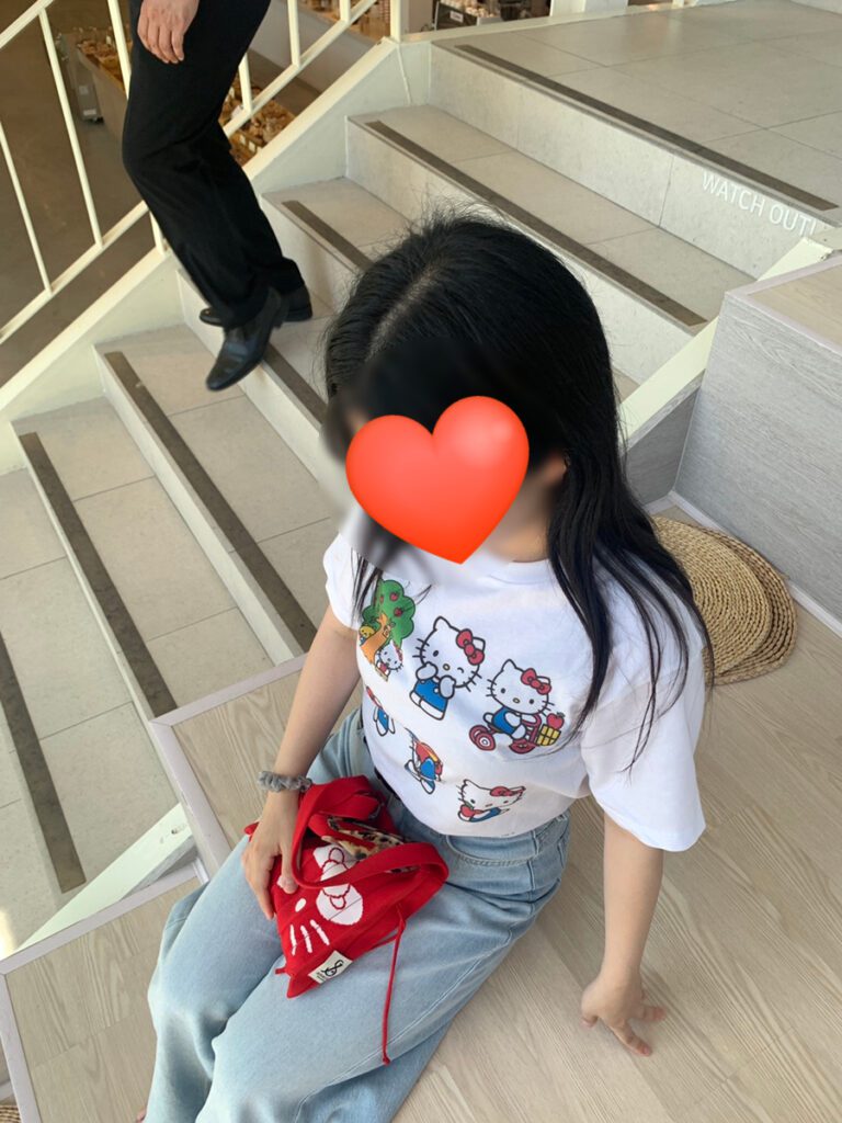 Sitting on stairs wearing UNIQLO Hello Kitty Custom T-shirt and holding red Kitty bag