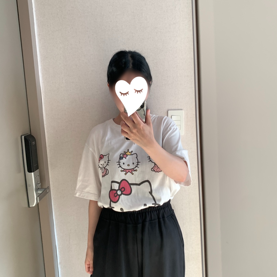 tucking Uniqlo Hello Kitty T-shirt into pants showing half-hidden Kitty print.