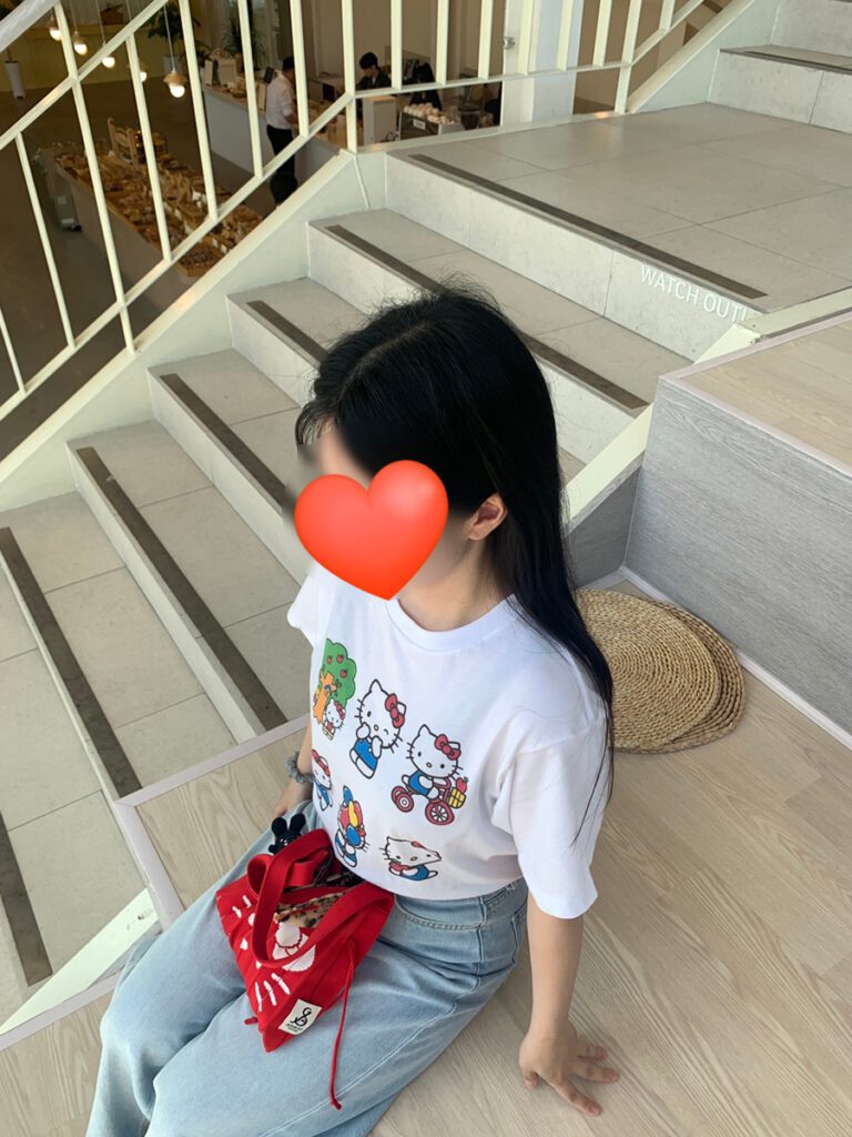 Close-up of UNIQLO Hello Kitty Custom T-shirt fit with red Kitty bag accent