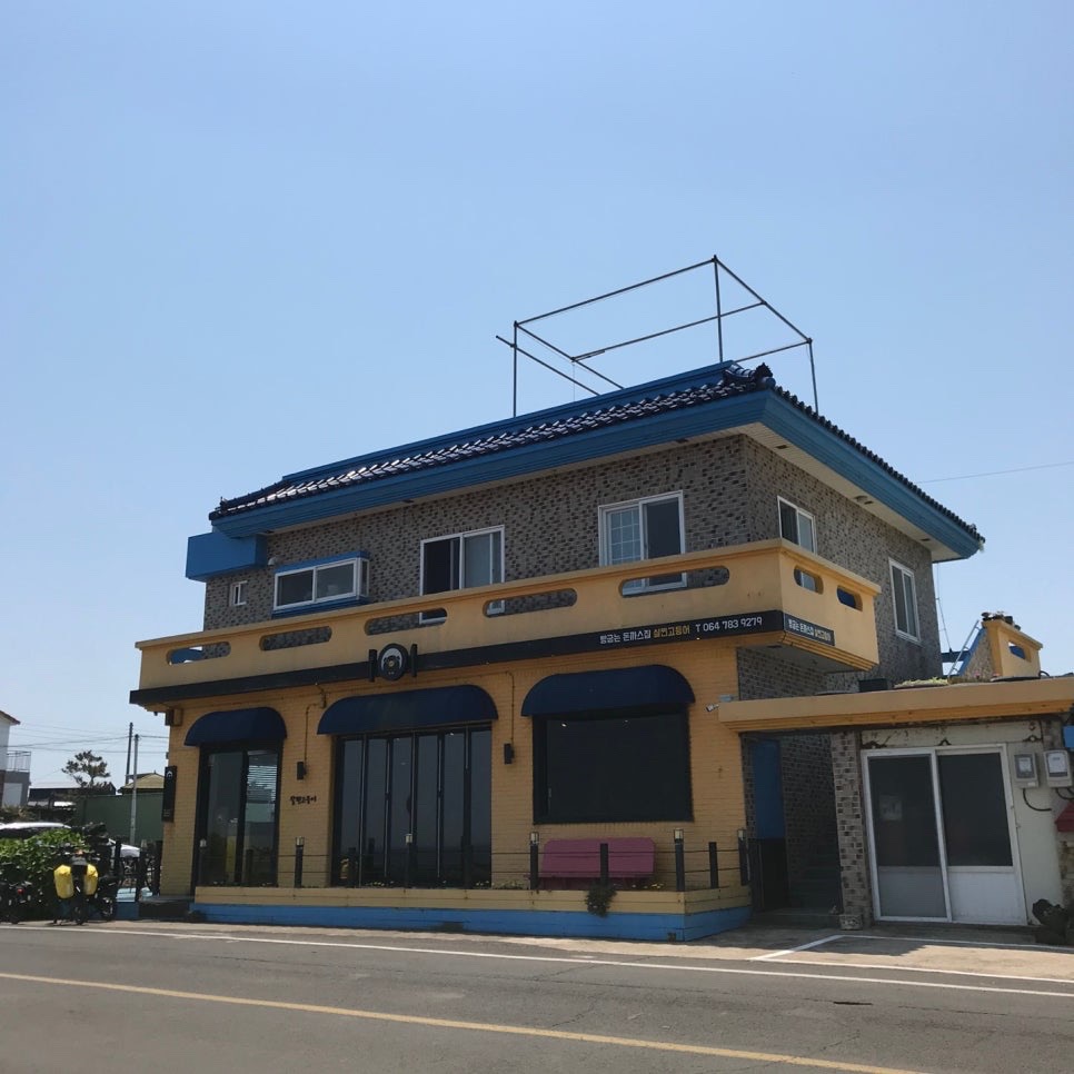 Bright yellow exterior of Saljingo Deungeo restaurant between Sehwa and Hado Beach in Jeju