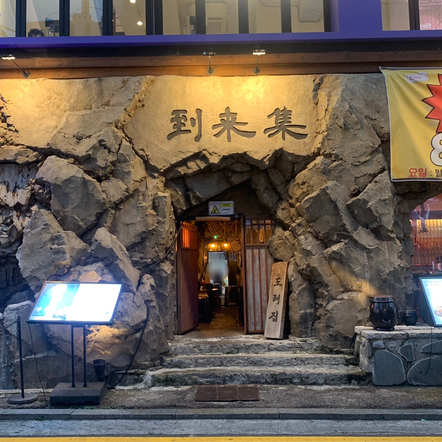 Right from the street, Doraejip catches your eye with its dramatic cave-style entrance carved into the stone. It instantly gives off a “hidden BBQ spot” vibe — like you’re about to enter a secret place only locals know about. This is exactly the kind of spot that makes eating near Gangnam Station feel exciting and different from the usual.
Walking inside, the warm lighting and rustic details make you feel like the perfect night is just about to start. A great first impression for a Gangnam Station makchang place!