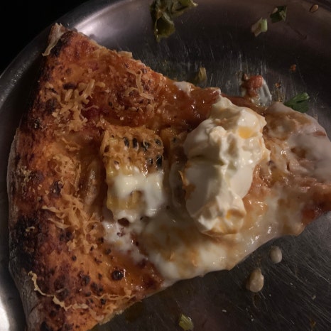 Pizza Never Sleeps Songridan-gil corn brown pizza slice with melted cheese