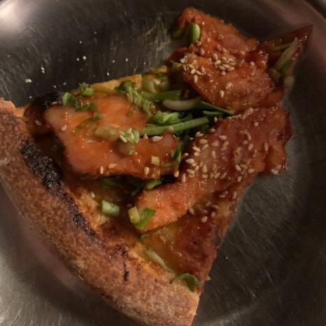 Pizza Never Sleeps Songridan-gil gochujang pork pizza slice with minari and sesame