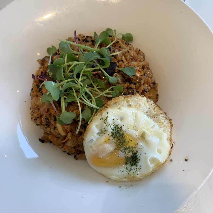 Kimchi fried rice topped with a fried egg and fresh sprouts