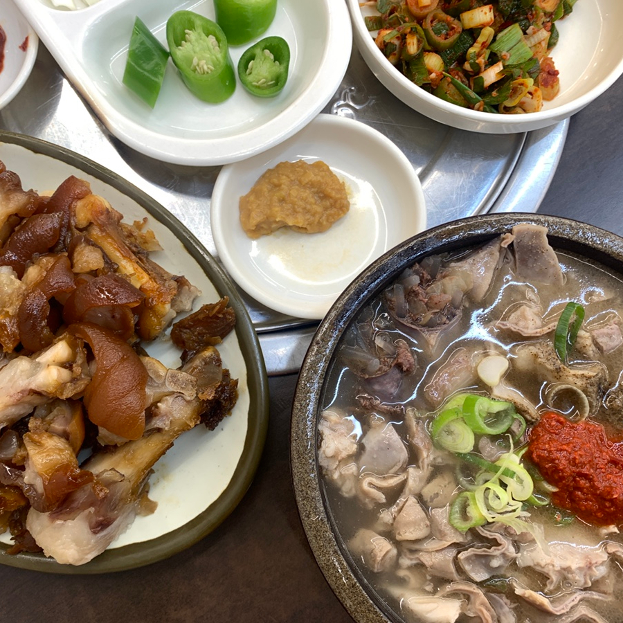 Traditional Korean pork soup meal with assorted side dishes and braised meat dishes