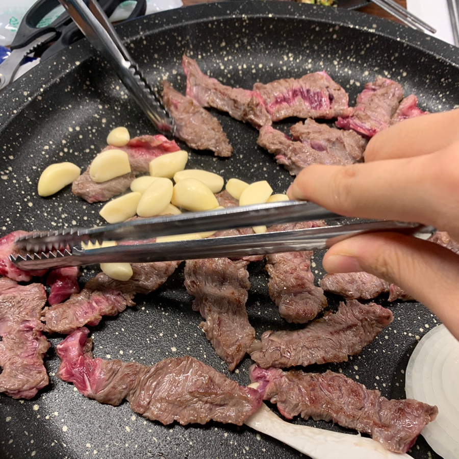 Tender beef cooking on the grill with roasted garlic at a Korean barbecue restaurant