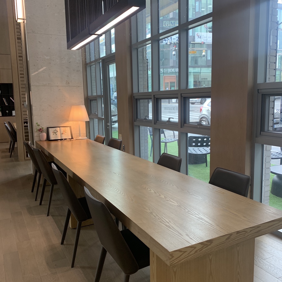 Spacious Cafe de Ladder interior with long wooden table by large windows