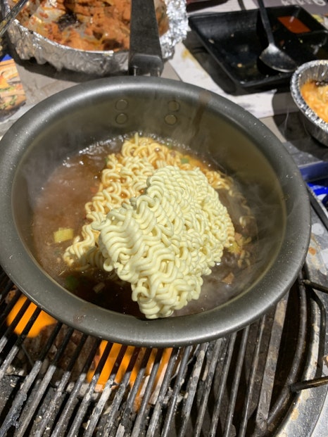 Ramen noodles cooking in seafood broth at Jogae Pocha Oido