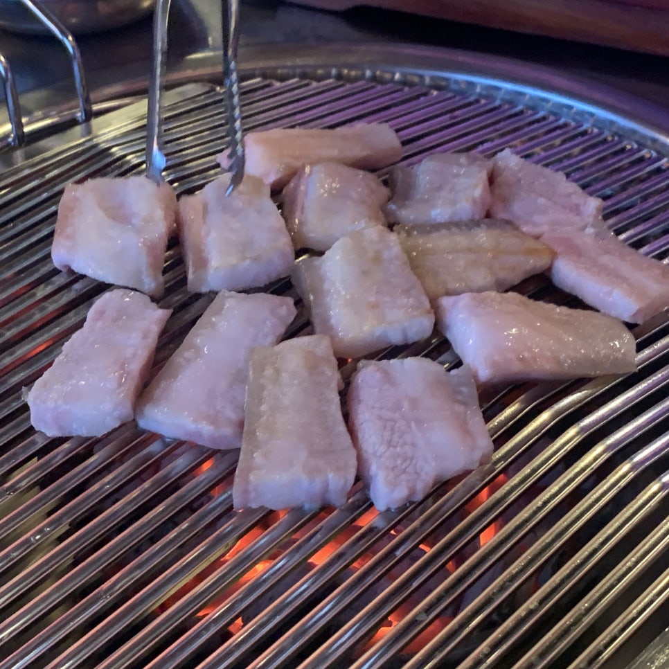 Charcoal grilled pork neck jowl and skin on a Korean BBQ grill
